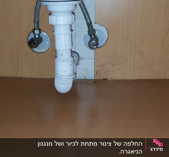 צינור ניקוז לבן מתחת לכיור בארון עץ